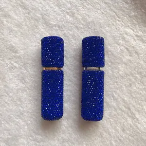 Pair of 10ml blue rhinestone portable refillable perfume spray bottles on white fur