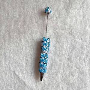 Detailed view of a beaded ballpoint pen decorated with blue butterflies and pearls