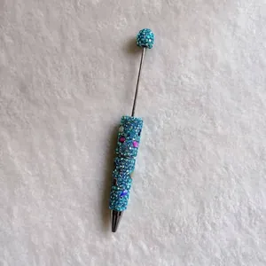 Close-up of a handmade pen fully encrusted with colorful blue rhinestones