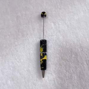 Detailed view of a handmade rhinestone ballpoint pen with black and yellow crystal pattern