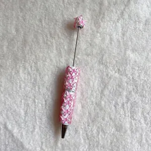 Close-up of decorative pink butterflies and pearls on a white beaded ballpoint pen
