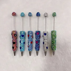 Detailed macro view of six colorful handmade rhinestone-encrusted pens with heart accents