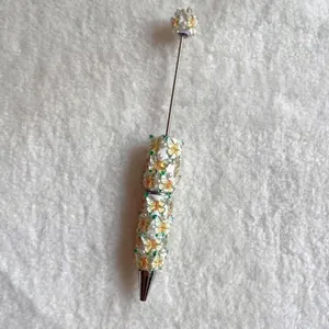 Close-up of decorative ballpoint pen with butterfly charms and pearls