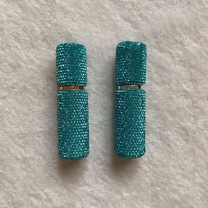 Close-up detail of two elegant teal rhinestone-encrusted 10ml portable perfume sprayers