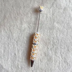 Detailed view of yellow butterfly beads and pearl accents on a custom beaded ballpoint pen