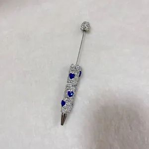 Macro detail view of handmade rhinestone pavé pen with elegant blue heart pattern accents