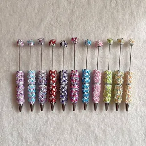 Detail view of colorful beaded pens with butterfly designs and decorative pearls