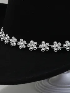 Primo piano della fascia decorativa con fiori di strass argento su cappello fedora nero.