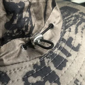 Detailed view of the adjustable drawstring toggle on a camouflage outdoor sun protection hat.