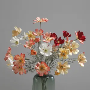 Close-up detailed view of colorful artificial cosmos flowers in a stylish green glass vase