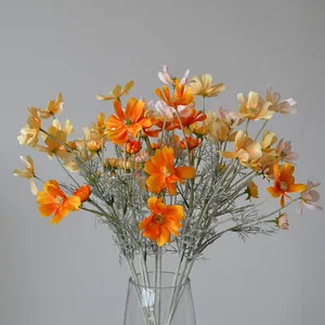Detailed view of vibrant orange and yellow silk artificial cosmos flowers in glass vase