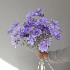 Detailed view of hand-held purple artificial cosmos flowers for home decoration