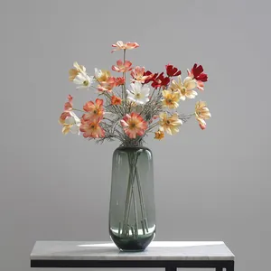 Detailed view of colorful artificial cosmos flowers in a sleek glass vase for home decoration