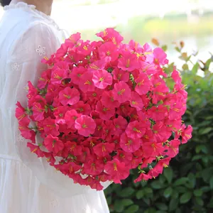 Vibrant pink artificial morning glory bouquet held by a person in a white lace dress
