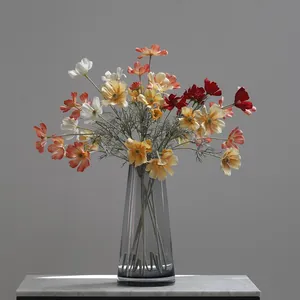 Detailed shot of multi-colored artificial cosmos flowers in a grey glass vase for home decor