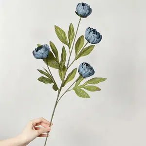 Handgehaltene Detailansicht einer realistischen blauen künstlichen Pfingstrose mit Blüten