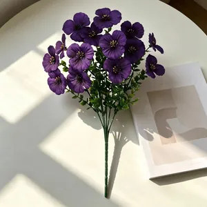 Nahaufnahme violetter Stiefmütterchen-Kunstblumen mit Eukalyptusstielen im natürlichen Sonnenlicht.