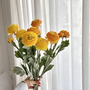Handheld bouquet of vibrant yellow and orange artificial Ranunculus flowers for home decor