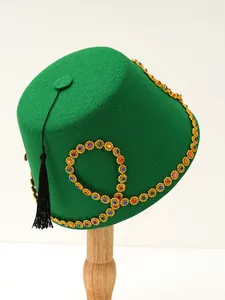 Detailed view of a green felt Turkish hat adorned with colorful jewels and a black tassel
