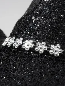 Détail d'un chapeau noir pailleté avec une bande décorative en strass fleuris argentés