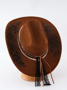 Dettaglio cappello cowboy in camoscio marrone con stampe di rose e nastri in pizzo