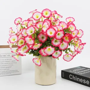 Close-up of vibrant pink artificial morning glory flowers in a cream ceramic vase.