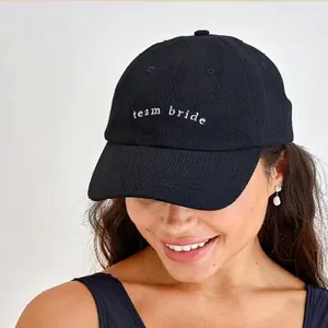 Close-up of black baseball cap featuring white team bride embroidery on a model