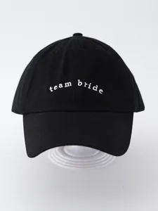 Close-up view of black cotton baseball cap featuring white 'team bride' embroidery