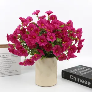Detailed view of fuchsia artificial morning glory flowers in a beige ceramic vase