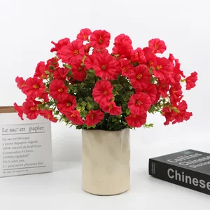 Detailed view of vibrant red artificial morning glory flowers in a cream ceramic vase