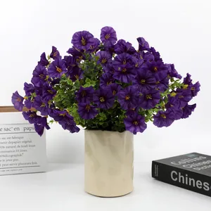 Detail view of vibrant purple artificial petunias with eucalyptus leaves in a vase