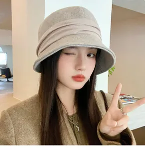 Close-up of a vintage Hepburn style pleated wool bucket hat in beige on a model