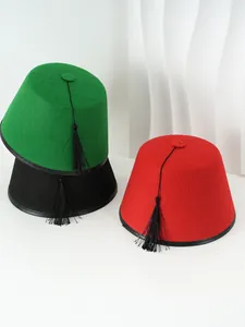 Detalle de sombreros turcos Fez de fieltro de colores con borlas negras en blanco