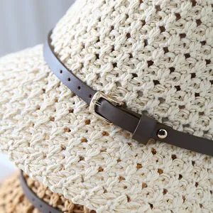 Close-up view of a crochet straw sun hat featuring a decorative brown leather belt buckle