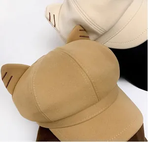 Dettaglio ravvicinato di cappelli newsboy in lana con orecchie di gatto in beige e crema.
