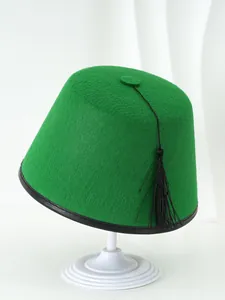 Sombrero Fez tradicional de fieltro verde clásico con borla negra en un soporte blanco