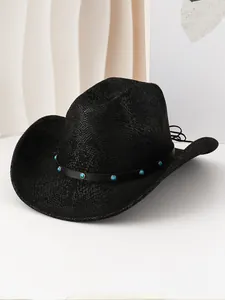 Détail d'un chapeau de cowboy noir à texture peau de serpent avec ruban turquoise.