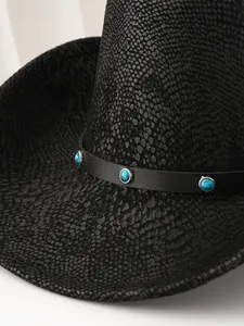 Vue rapprochée d'un chapeau de cow-boy noir avec texture peau de serpent et détails turquoise