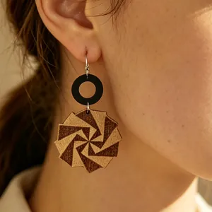 Primo piano di orecchini geometrici in legno con stampa a spirale a forma di mulino a vento.