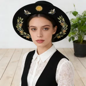 Close-up detail of black gothic flat brim hat featuring sun and bee embroidery motifs.
