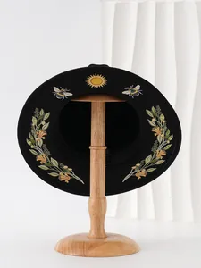 Detail view of gothic black hat featuring sun and bee embroidery patterns on brim