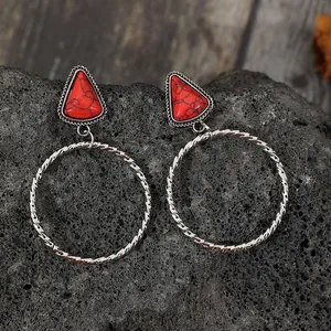 Dettaglio orecchini bohémien con pietre rosse triangolari e grandi cerchi argentati.