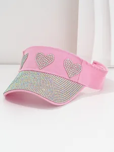 Detailed macro view of pink sun visor hat featuring sparkling rhinestone heart patterns