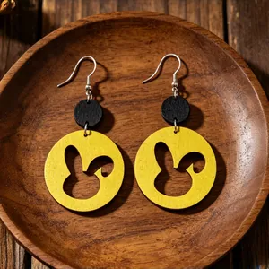 Dettaglio macro di orecchini di legno a forma di coniglio giallo nero su legno