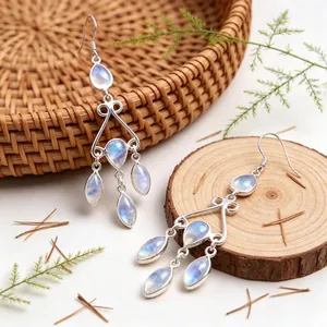 Primer plano detallado de pendientes bohemios de plata con gotas de piedra de luna azul radiante.