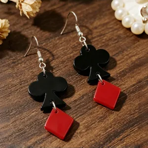 Close-up of black club and red diamond acrylic poker card drop earrings on wood.