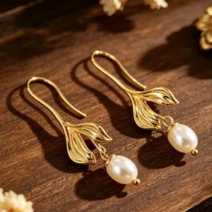 Primer plano de pendientes cola de sirena dorados con elegantes perlas blancas colgantes