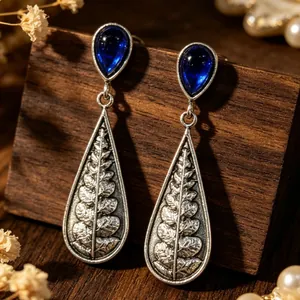 Detailed view of vintage silver-tone teardrop earrings with blue stone and fern leaf engraving