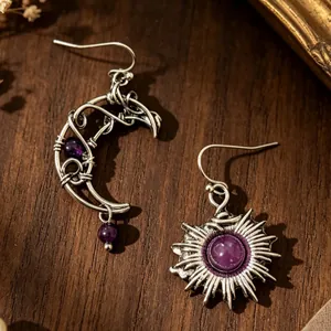 Detalle de pendientes hechos a mano de sol y luna con amatista y diseño envuelto en plata antigua