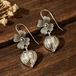 Squisiti orecchini vintage in argento con fiori e boccioli su un fondo di legno scuro